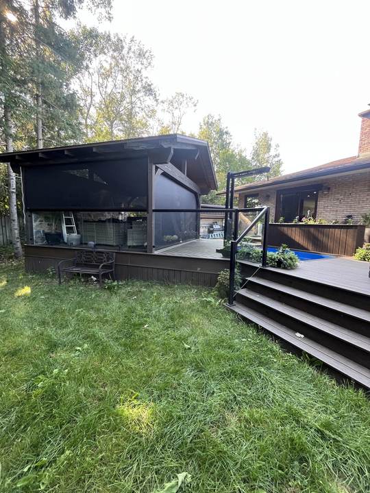 Backyard deck with screened porch panels, stairs and a lawn