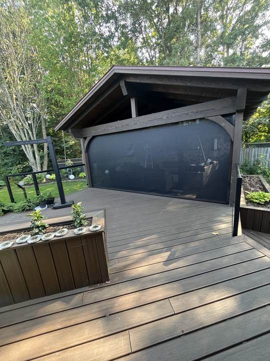 Dark wood deck with a screened porch and planter boxes